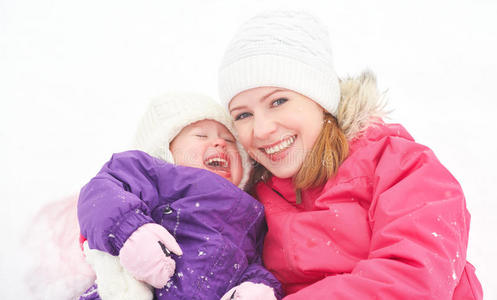 幸福的家庭母亲和女婴女儿在冬雪中嬉笑
