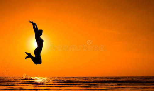 在海上夕阳中跳跃的女孩