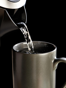 现代水壶向杯子里倒水隔离在黑色上