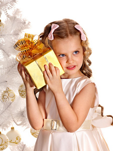 在白色圣诞树旁拿着礼品盒的孩子。