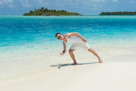 一个人在白色的海滩上溅起蓝色的海水