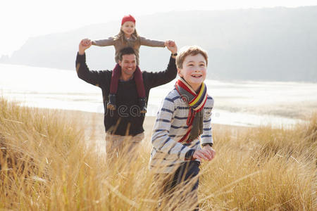 父亲和孩子们在冬日海滩上穿过沙丘