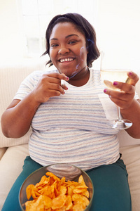 超重妇女在家吃薯条喝葡萄酒