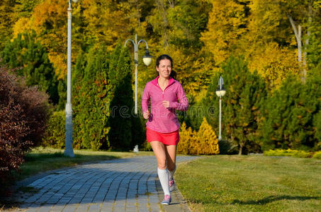 秋天公园里的女人跑步，美丽的女孩跑步者在户外慢跑