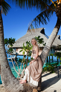 在海边的棕榈树上，一个穿着长裙的漂亮女人。