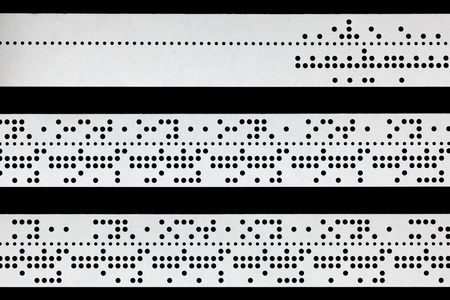阅读打卡在黑色背景上的穿孔穿孔纸带的特写照片
