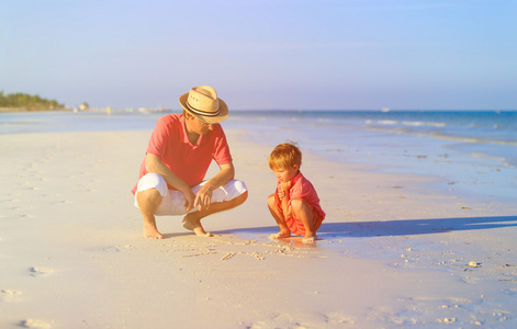 父亲和儿子在夏天的海滩上绘图