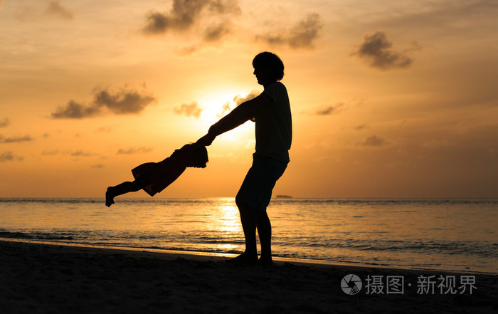 父亲和小女儿在日落时发挥剪影