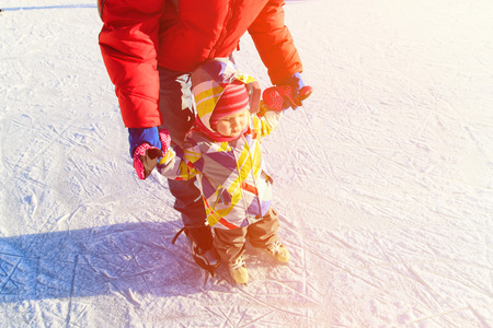 父亲和小女儿学习在冬天滑冰