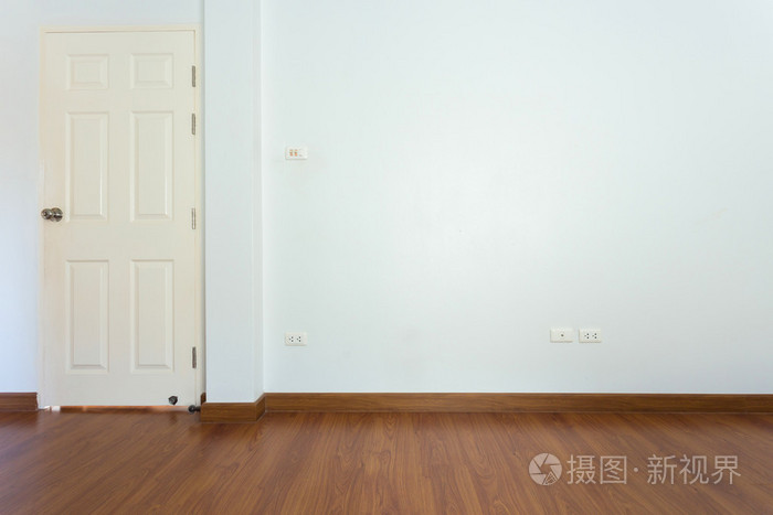 空旷的房间里棕色木地板和白胶浆墙