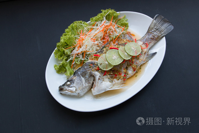 鱼菜在黑色背景上蒸鲷鱼配柠檬