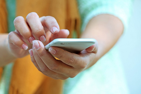 双手拿手机女性双手拿手机的户外活动,对模糊的背景照片