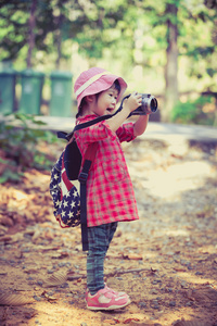 亚洲女孩拍照的数码相机在花园里。老式的图片样式