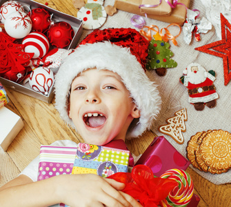 小可爱的孩子，在红色的圣诞老人帽子与手工礼品，玩具老式木制，温暖冬天