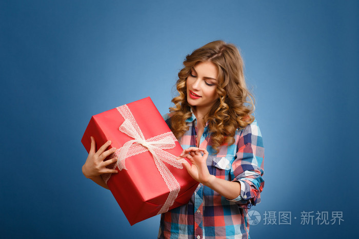 年轻的女孩，在一个红色的圣诞礼品包装一个盒子