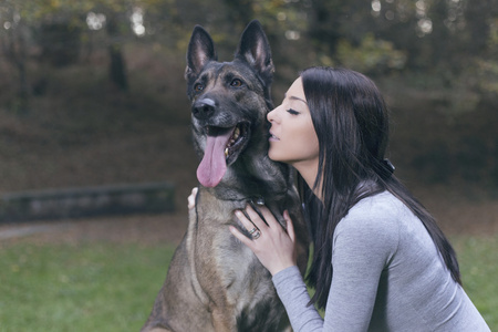 年轻女子和她的玛利诺犬狗在公园里玩照片