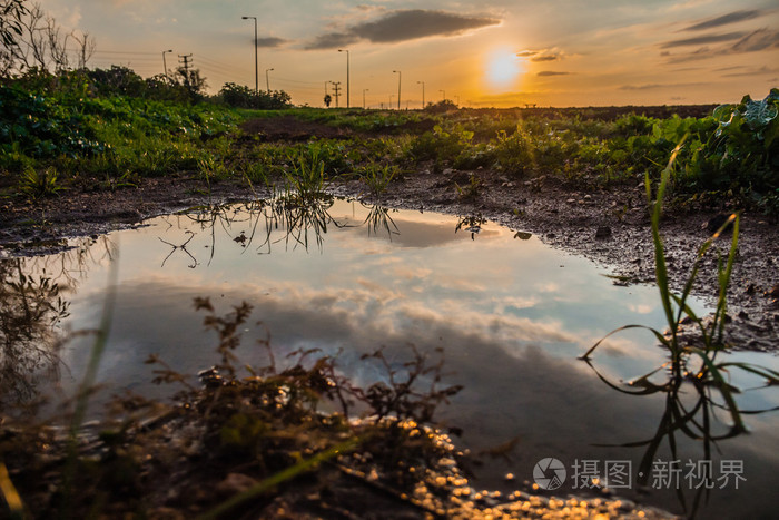 日落时, 天空反映在田野里的水坑里