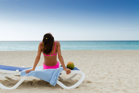 年轻女子躺在用椰子，海边的躺椅上，