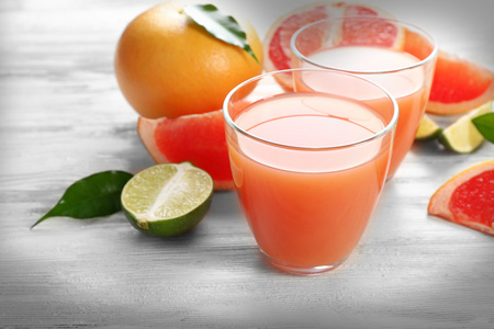 柑橘类果汁和新鲜水果轻木背景上的两杯