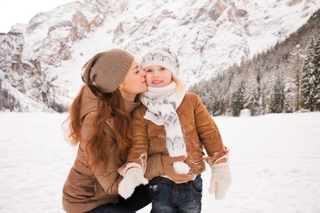 在白雪覆盖的群山中，母亲在户外亲吻孩子