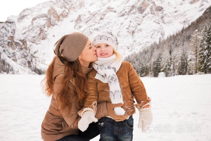 在白雪覆盖的群山中母亲在户外亲吻孩子