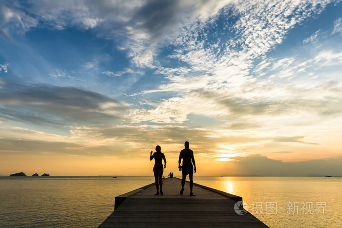 夫妻在码头上在日落时分在一个热带岛屿上散步