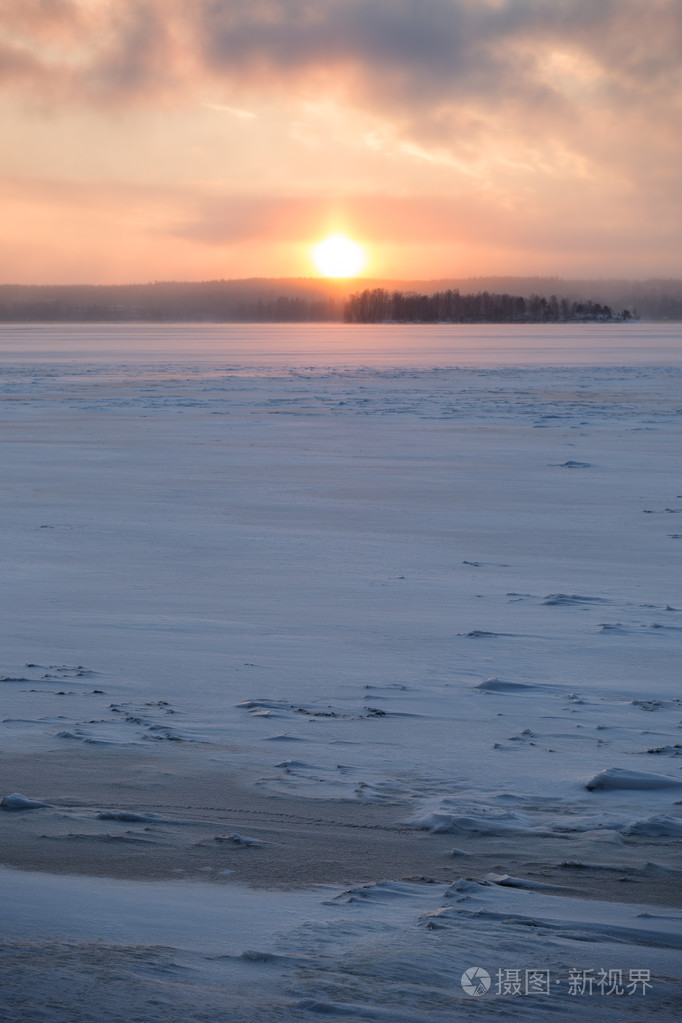 在芬兰冰冻多雪的湖面上日出