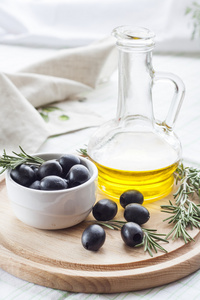 瓶橄榄油和腌制的黑橄榄。在陶瓷碗和木勺与瓶橄榄油腌黑橄榄