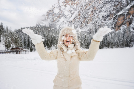 穿着皮帽子的快乐女人站在超级运动员面前扔雪