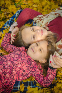 幸福的母亲和女儿躺在秋天的公园