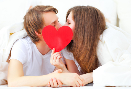 爱人情侣亲吻着躺在床上一颗红心