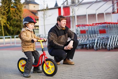 蹒跚学步的自行车和他的父亲在这座城市的小男孩