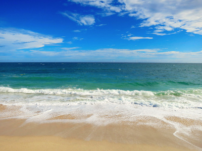 平静的热带海滩，与白砂和绿松石水蓝色多云的天空下