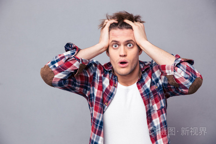 震惊茫然的年轻人抱着头用两只手