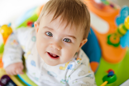 小宝贝男孩坐在一个色彩缤纷的宝宝沃克玩具和在家在幼儿园里，微笑特写