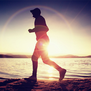 运动员戴棒球帽,慢跑在以上海上日出照片