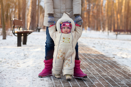 一个幸福的家庭。妈妈教孩子学会走路在冬季公园