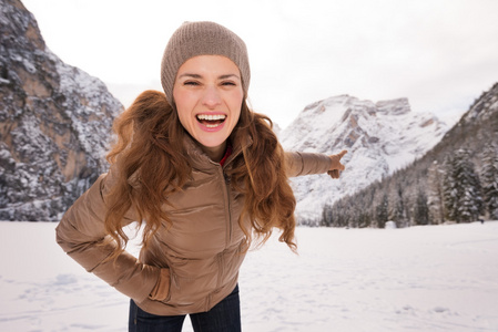 户外的快乐年轻女子指着雪山