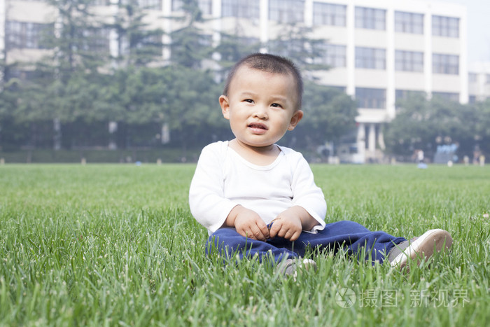 可爱的中国小男孩坐在草地上