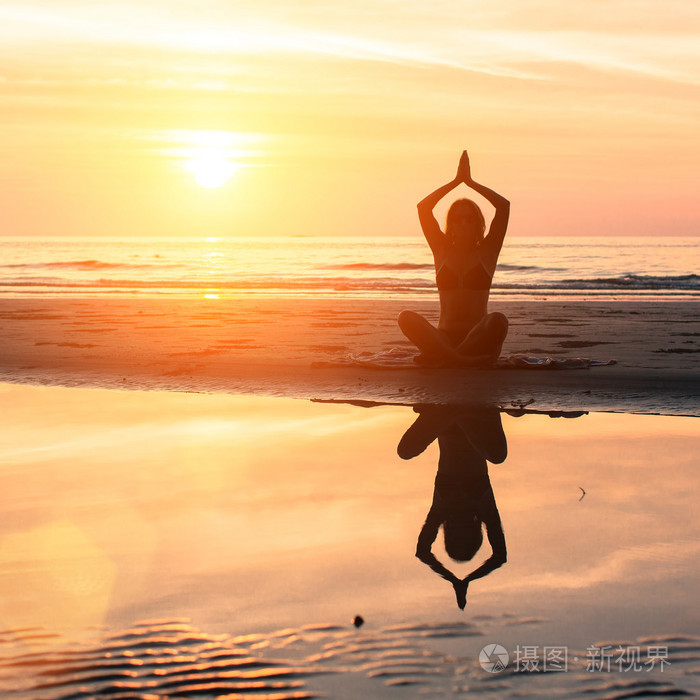 女人练瑜伽在海滩上