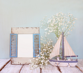 旧的老式木制框架 白色的花和帆船木制的桌子上。老式的滤波的图像。航海生活方式的概念。模板，准备把摄影