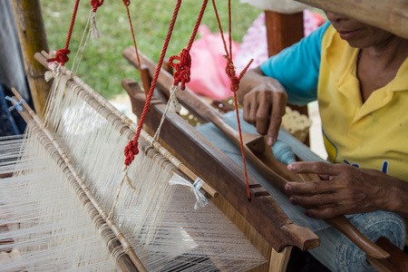 女人用传统方式在手工织机织造丝绸。泰国