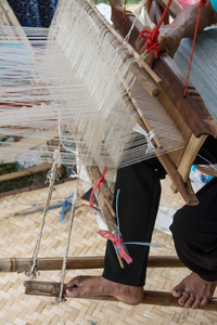 女人用传统方式在手工织机织造丝绸。泰国