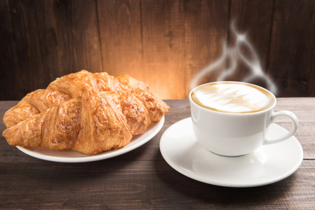 早餐杯咖啡和羊角面包木制的桌子上
