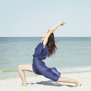 做瑜伽在海边穿着蓝色衣服的年轻美丽的女人