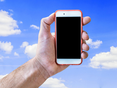 手拿着触摸屏手机孤立在多云的蓝色天空