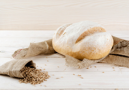 白色面包，谷物和小麦小穗躺在白色的木桌上