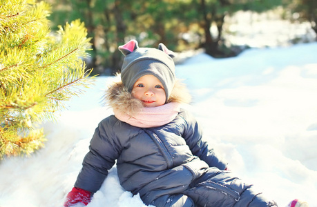 快乐的小孩玩坐在雪地上，在冬季的一天
