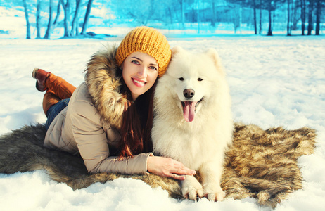 快乐微笑的女老板和白色的萨摩耶狗躺在雪