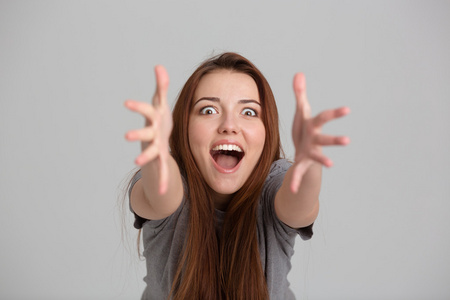 高兴兴奋的年轻女子大声喊叫,伸手拍镜头照片